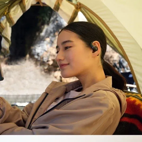 イヤホンを装着してキャンプする女性