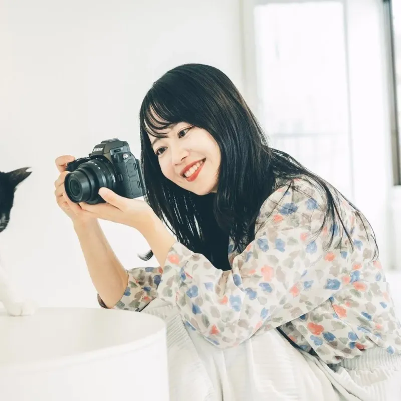 カメラを構え笑顔の女性と猫