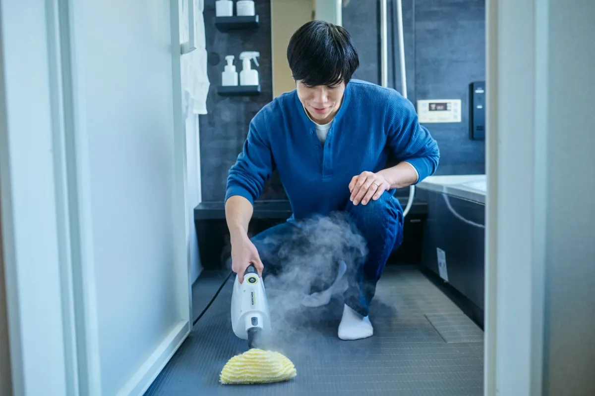 浴室の床をスチームクリーナーで掃除する男性