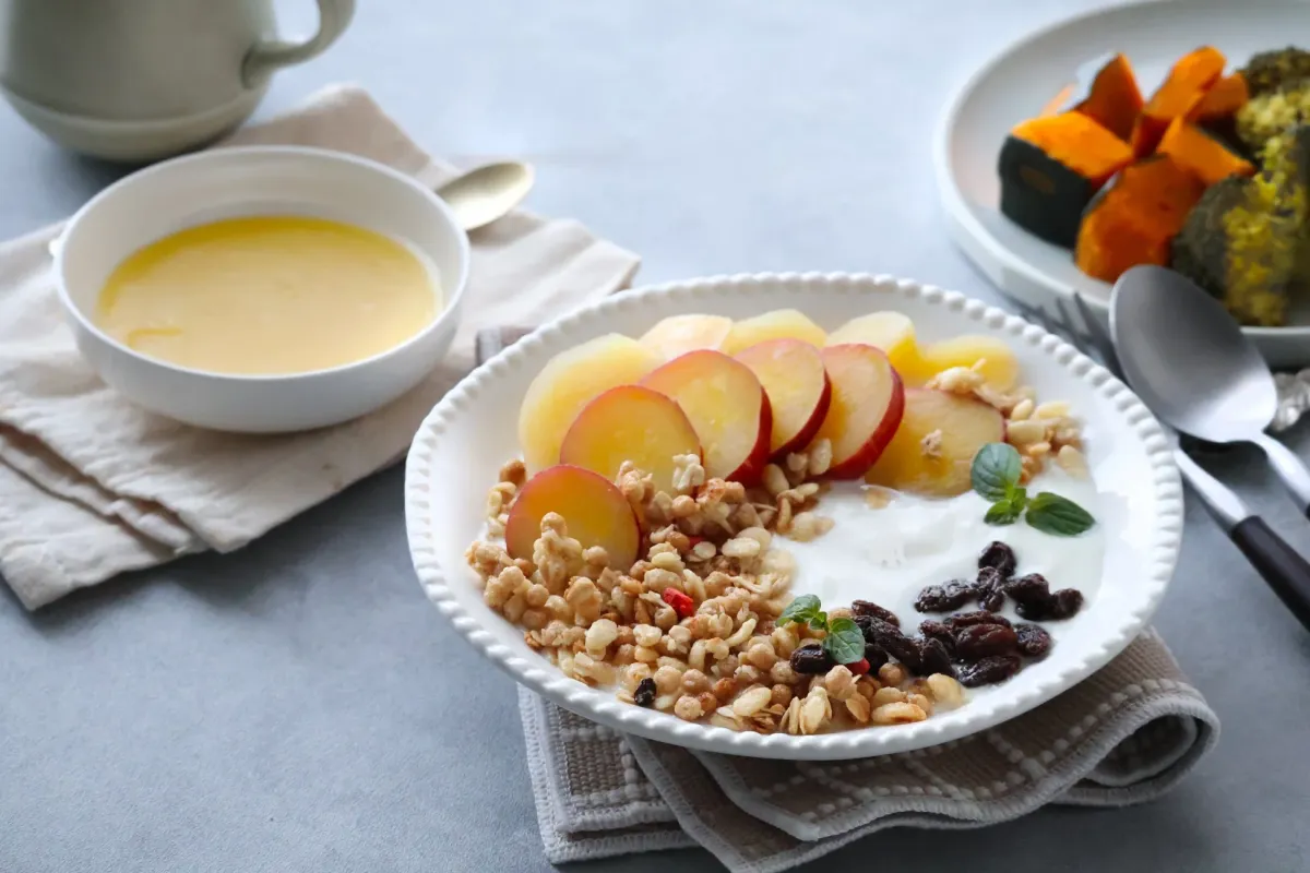 朝食のテーブルに、グラノーラ、ヨーグルト、スープ、温野菜