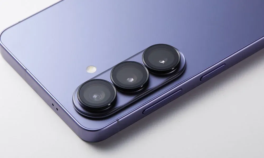 紫色のスマートフォンの背面をクローズアップした画像。水平に並んだトリプルカメラレンズとフラッシュが特徴で、洗練されたデザインのモバイルデバイスを示しています。