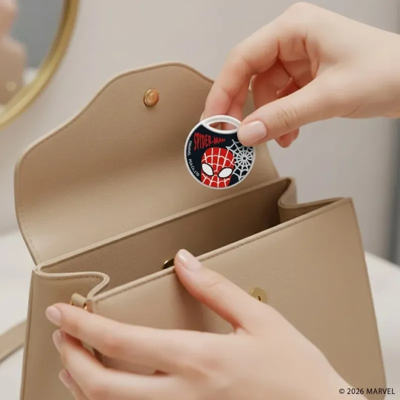 スパイダーマンデザインのキーホルダーをハンドバッグに入れる様子