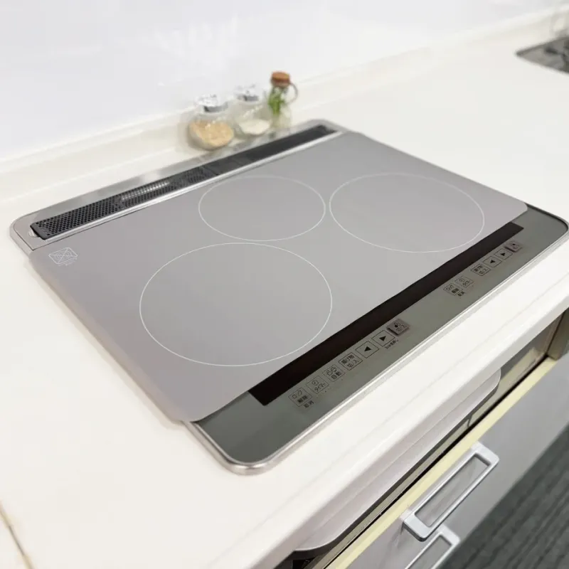 清潔感のあるモダンなキッチンに設置されたIHクッキングヒーターを捉えた画像です。複数の調理ゾーンと操作パネルが見え、奥には調味料の瓶が置かれています。機能的で整頓された調理空間の様子が伺えます。