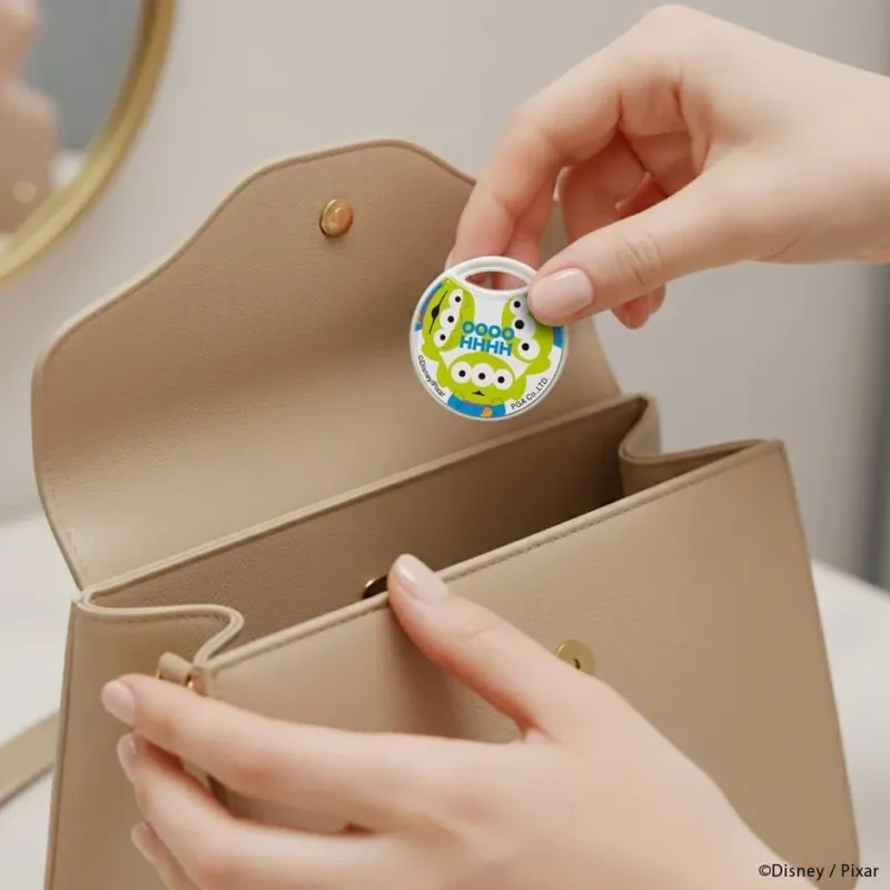 リトルグリーンメンがデザインされた小物をハンドバッグに入れる様子