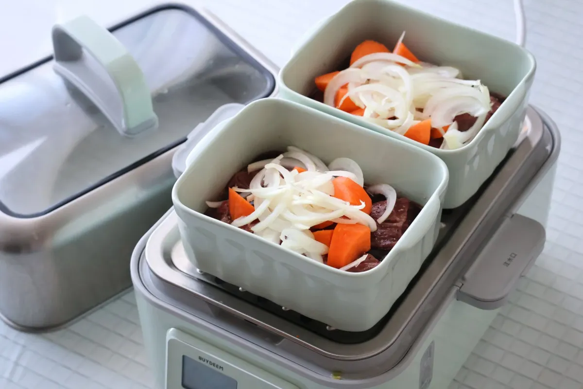 電気調理器具に、レバー、にんじん、玉ねぎが入れられた2つの容器がセットされている様子