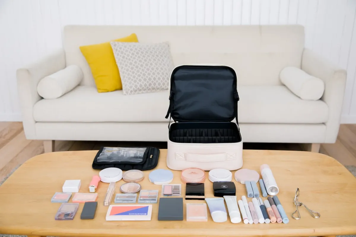 木のテーブルの上に化粧品やメイク道具、メイクアップケースが広げられている。