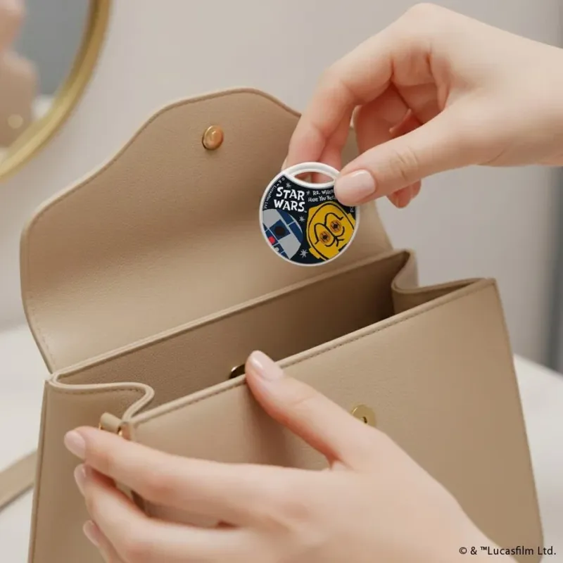 R2-D2とC-3POがデザインされたチャームをハンドバッグに入れる様子