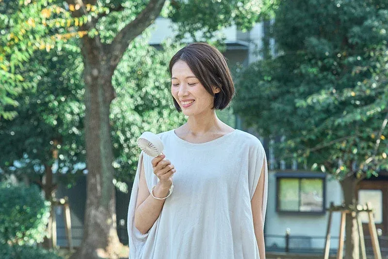 屋外でハンディファンを使用する女性
