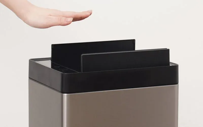 非接触型の自動開閉式ゴミ箱または同様のデバイスの上で、手がセンサーに反応している様子を捉えた画像です。衛生的な操作を示唆しています。