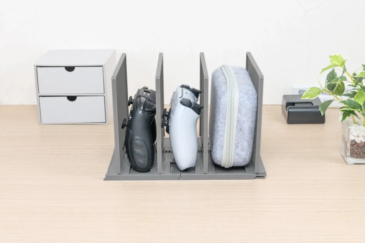 デスク上の収納スタンドにゲームコントローラーとポーチが収納されている様子