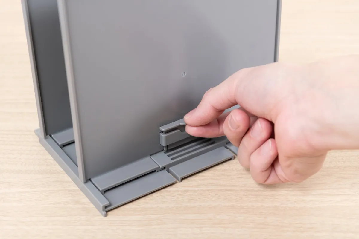 灰色のプラスチック製収納用品を調整する手